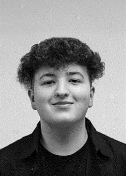 A photograph of Ruslan Mukhamedvaleev smiling in black and white.